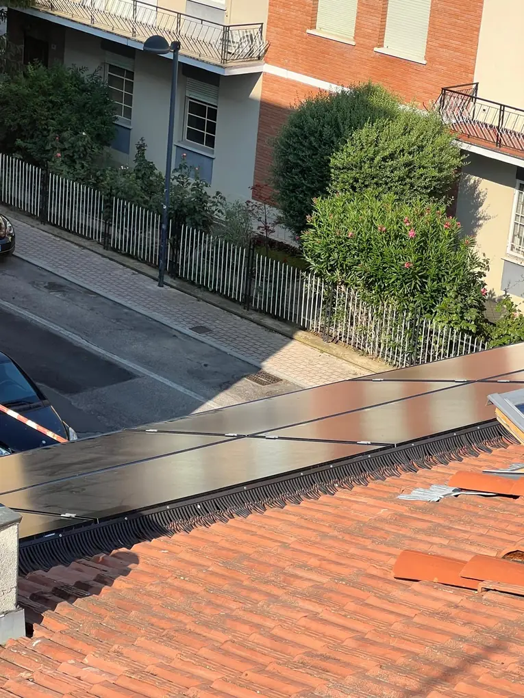 Barriera anti-piccioni scura, poco visibile, sotto pannelli fotovoltaici neri