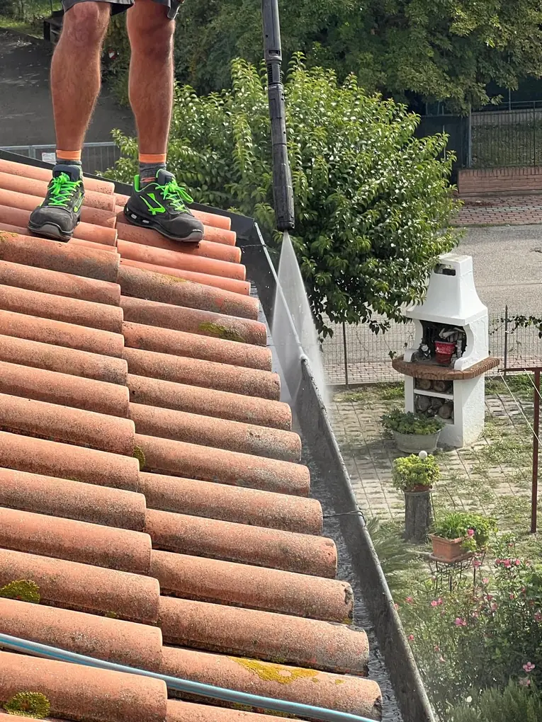 Lavaggio della grondaia per rimuovere guano, foglie e residui