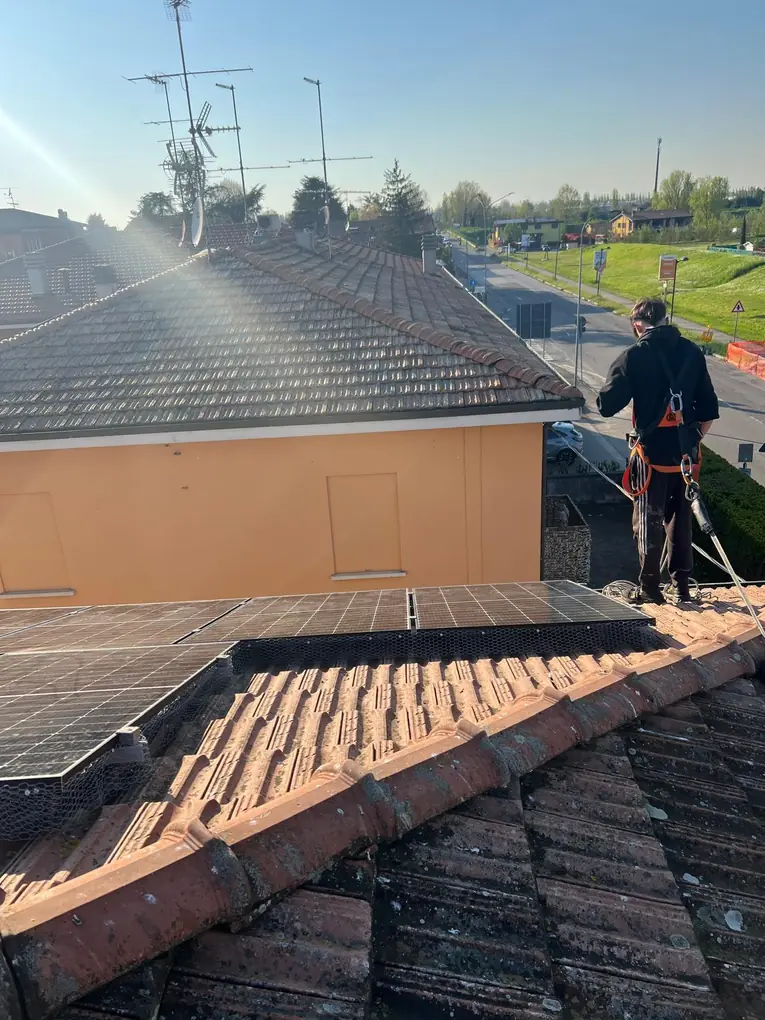 Operatore agganciato alla linea vita sul colmo di un tetto con fotovoltaico protetto