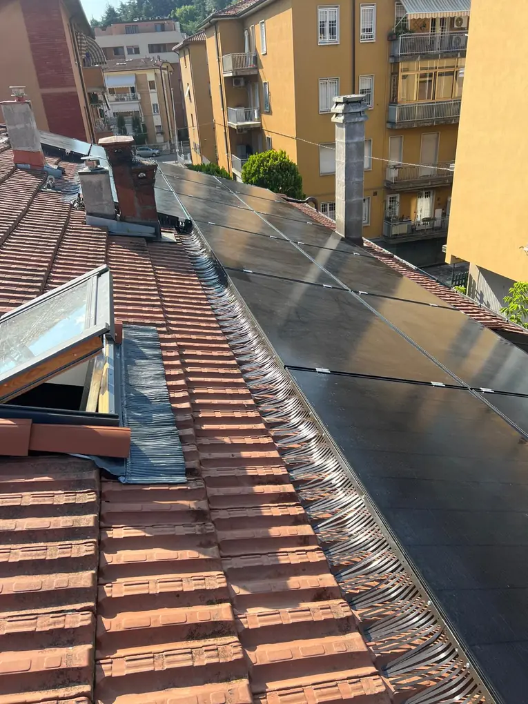 Barriera anti-piccioni sotto pannelli fotovoltaici full black accanto a un lucernario