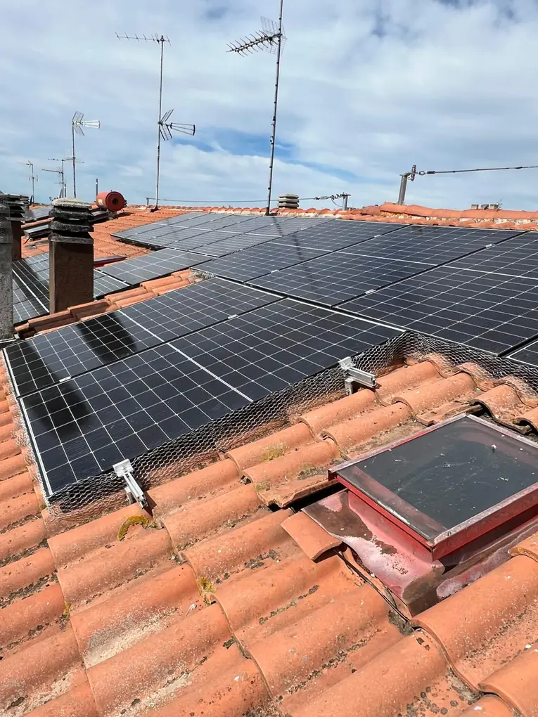 Rete anti-piccioni sotto i pannelli fotovoltaici su tetto in coppi in città